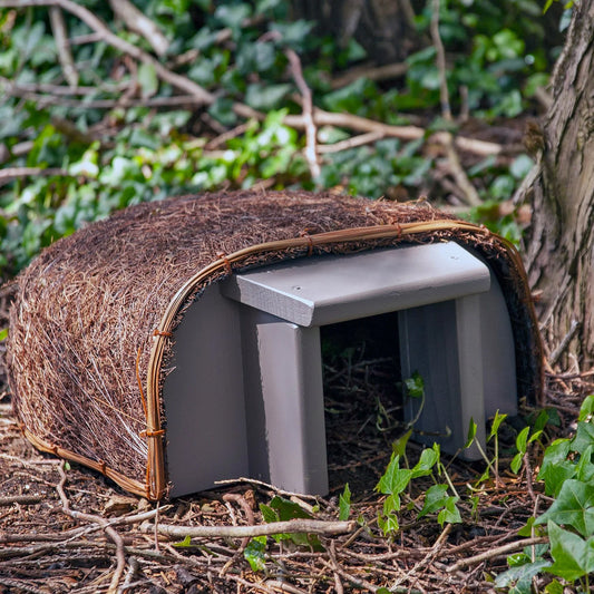 Side view of the Wildlife World Timeless Hedgehog Haus showing waterproof felt roof, rattan edging, and sturdy steel frame construction
